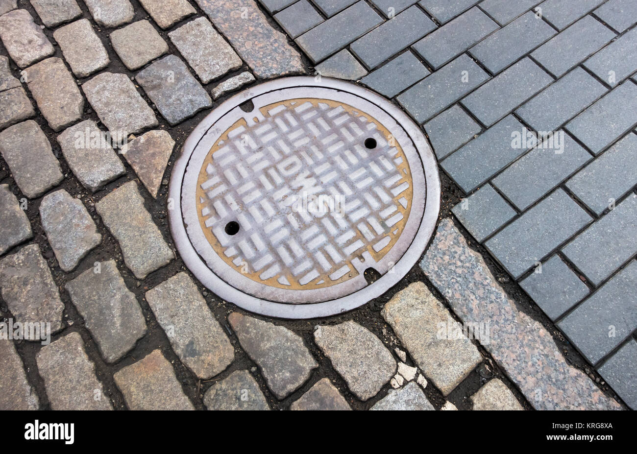 Eine Mischung aus Kopfsteinpflaster Typen um einen Abwasserkanal in Lower Manhattan. Stockfoto