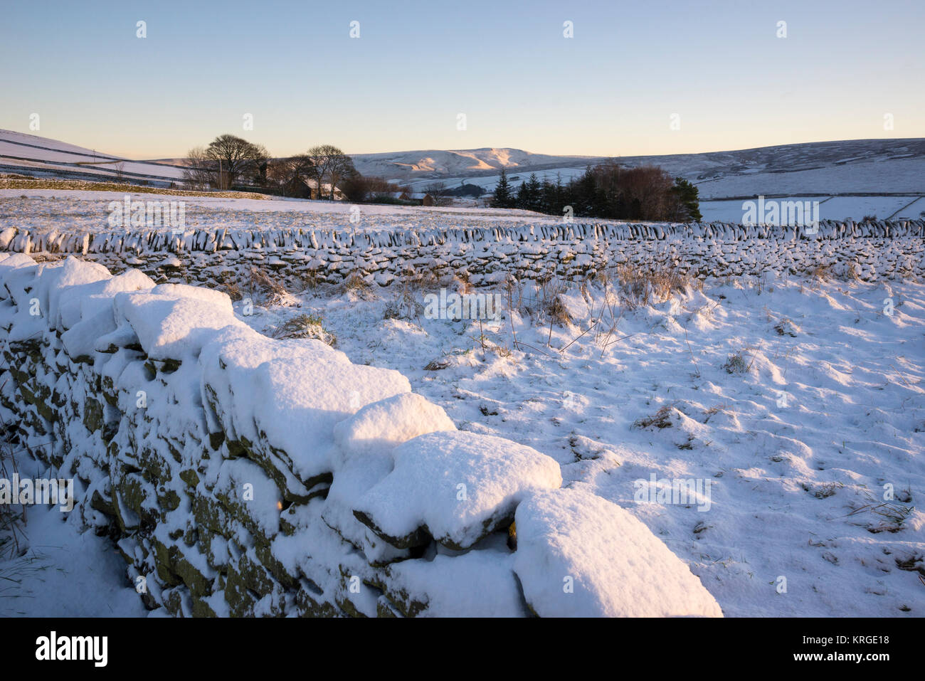 Blick über verschneite Felder auf die fernen Hügel auf einer klaren Wintermorgen. Rowarth, Derbyshire, England. Stockfoto