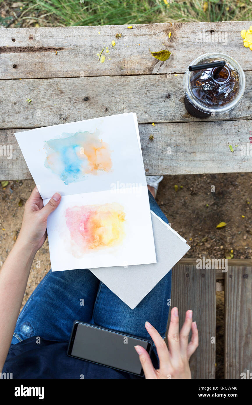 Asiatische Mädchen Zeit mit Papier Kunst und kalten Drink auf hölzernen Tisch Lifestyle in der Natur entspannen Stockfoto