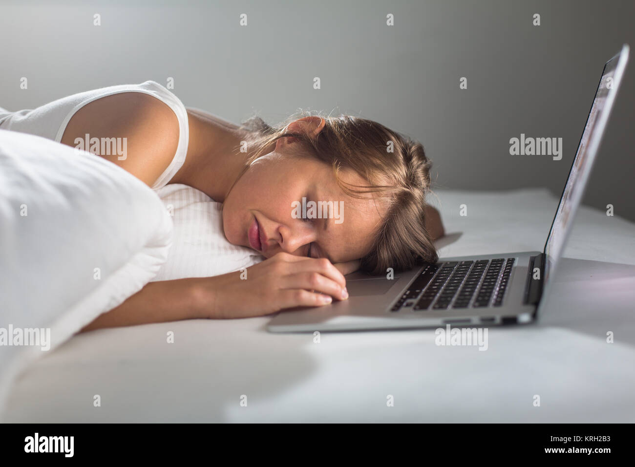 Hübsche junge Frau schlief, während auf Ihrem Laptop im Bett arbeiten Stockfoto