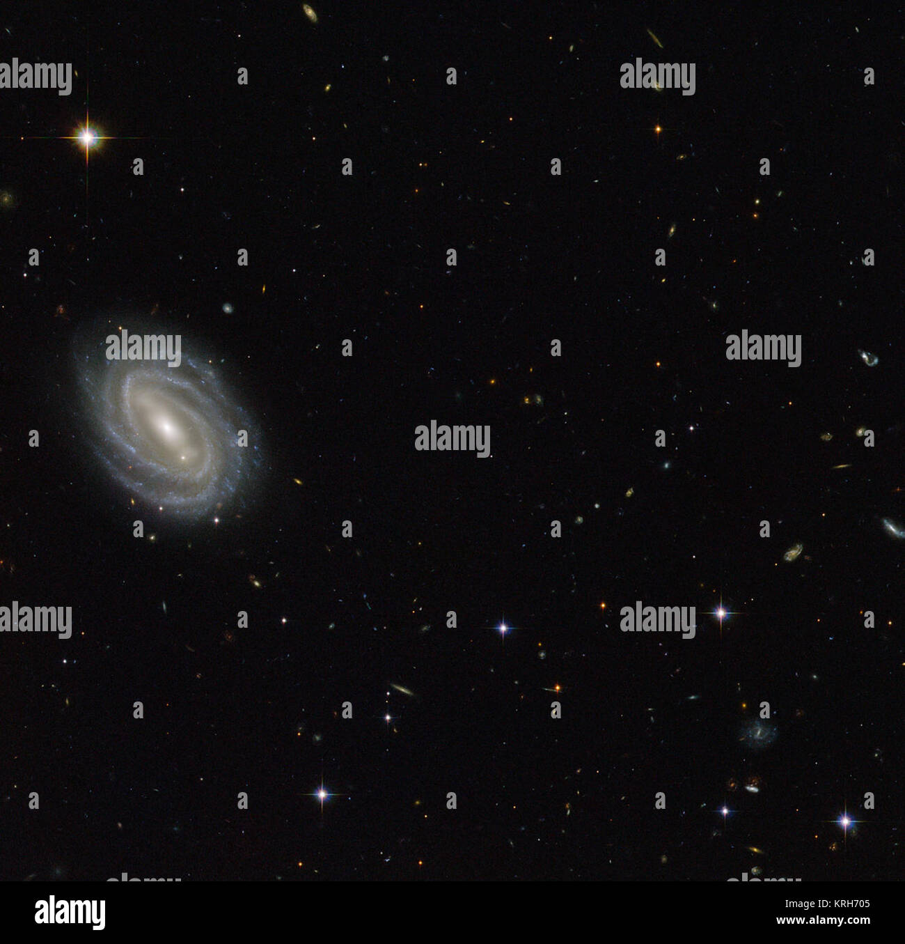 Diese neue NASA/ESA Hubble Space Telescope Bild zeigt eine schöne Spiralgalaxie bekannt als PGC 54493, entfernt im Sternbild Serpens (Die Schlange). Diese Galaxie ist Teil eines Galaxienhaufens, die von den Astronomen entdecken eine faszinierende Phänomen, wie die Schwachen Gravitationslinseneffekts untersucht wurde. Dieser Effekt, verursacht durch die ungleiche Verteilung der Materie (einschließlich dunkle Materie) im gesamten Universum, über Umfragen, wie z. B. das Hubble Medium Deep Survey untersucht wurde. Die dunkle Materie ist eines der großen Rätsel der Kosmologie. Es verhält sich ganz anders als gewöhnliche Materie, da er keine em Stockfoto