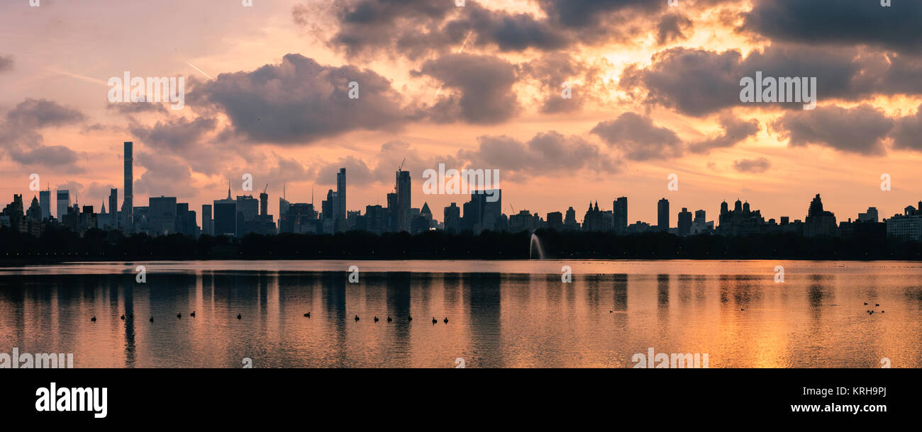 Ein rosa winter Sonnenuntergang über der Hell's Kitchen und Midtown mit dem Gebäude in der Jaqueline keneddy Onassis Reservoir im Central Park, Manhatta wider Stockfoto
