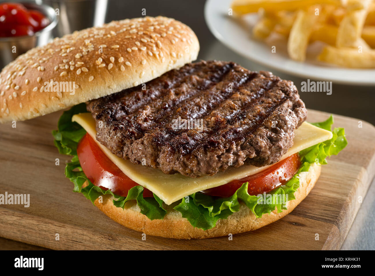 Eine köstliche gegrillte Angus Burger mit Käse, Salat und Tomaten auf einer Sesamsaat bun. Stockfoto