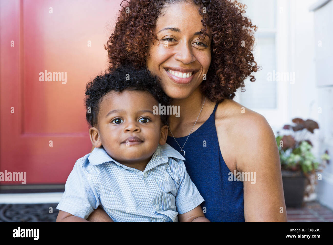 Lächelnd Mischlinge Mutter und Baby Sohn sitzt auf der vorderen Stoop Stockfoto
