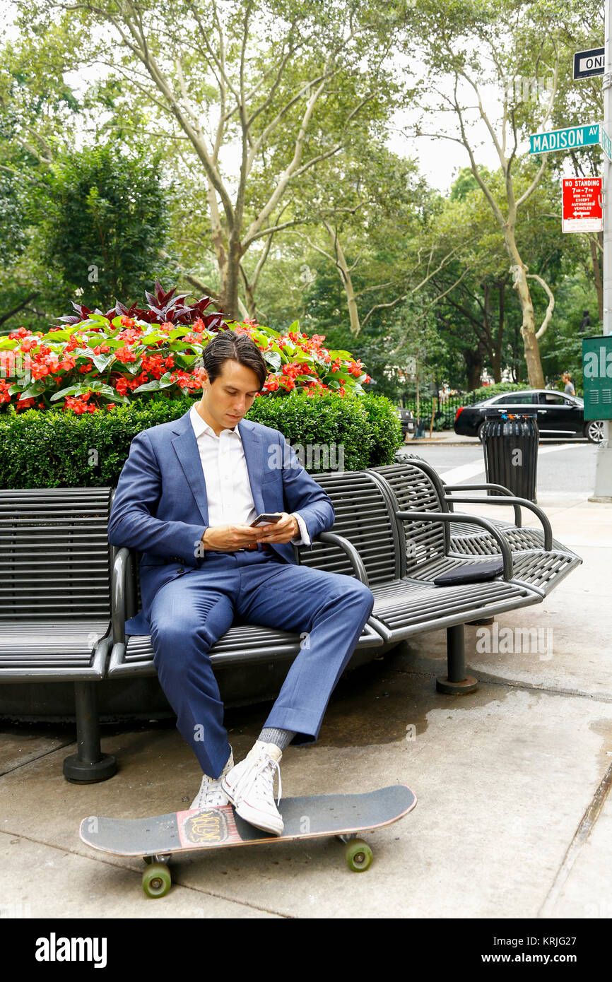 Kaukasische Geschäftsmann auf parkbank SMS auf Handy Stockfoto