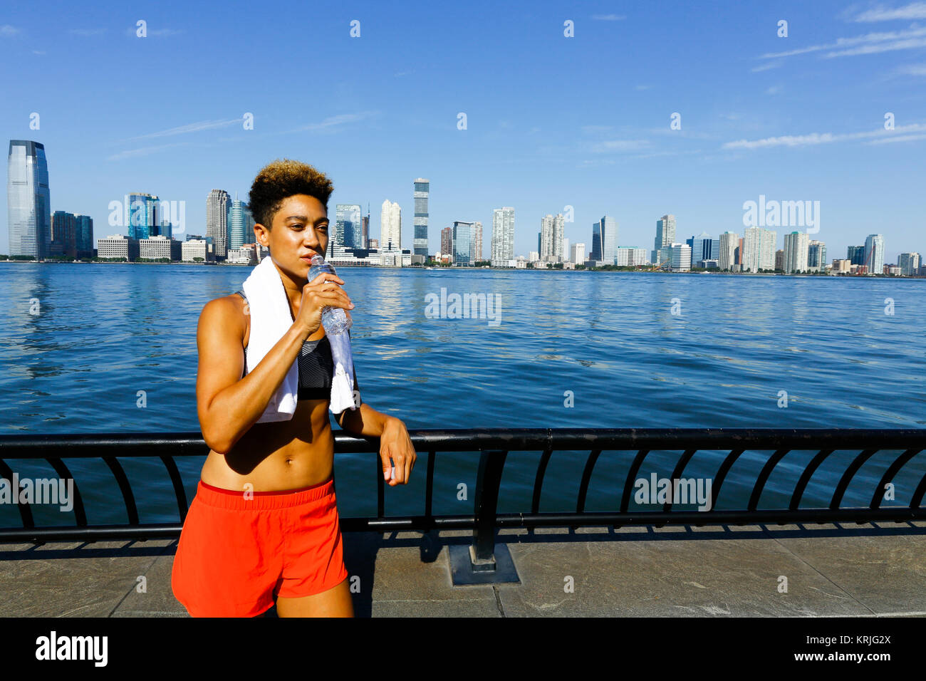 Gemischte Rasse Frau trinkt Wasser aus der Flasche im Waterfront Stockfoto