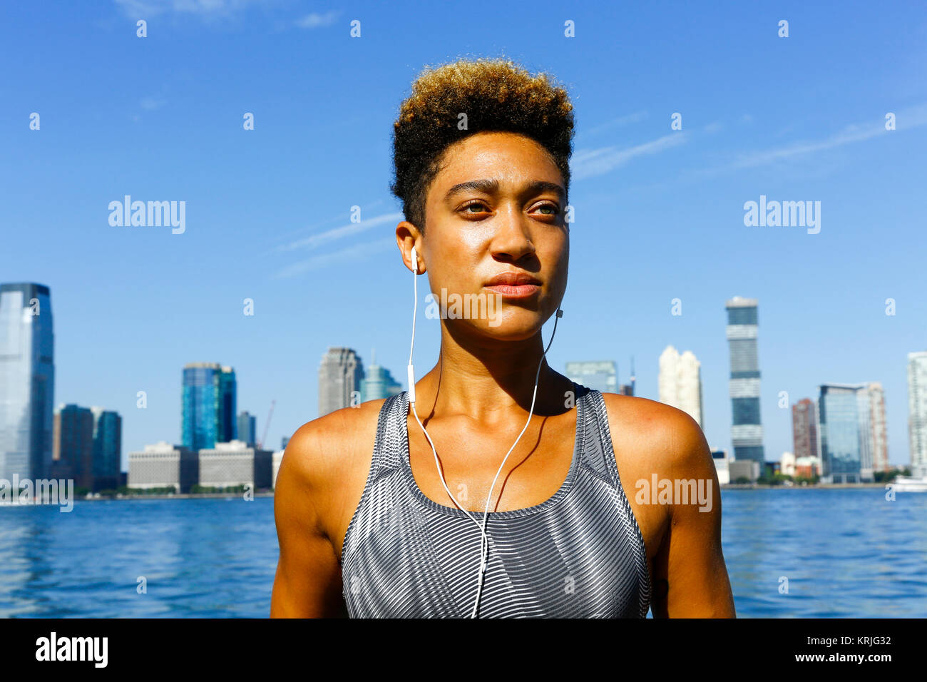 Gemischte Rasse Frau im Waterfront hören Ohrhörer Stockfoto