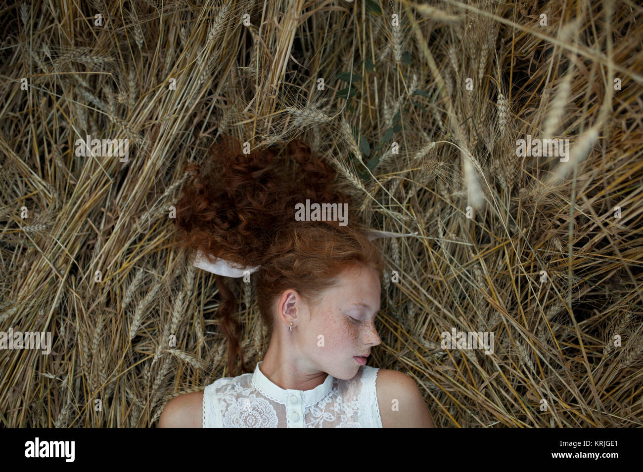 Ernsthafte kaukasische Mädchen mit Sommersprossen Festlegung in Weizen Stockfoto