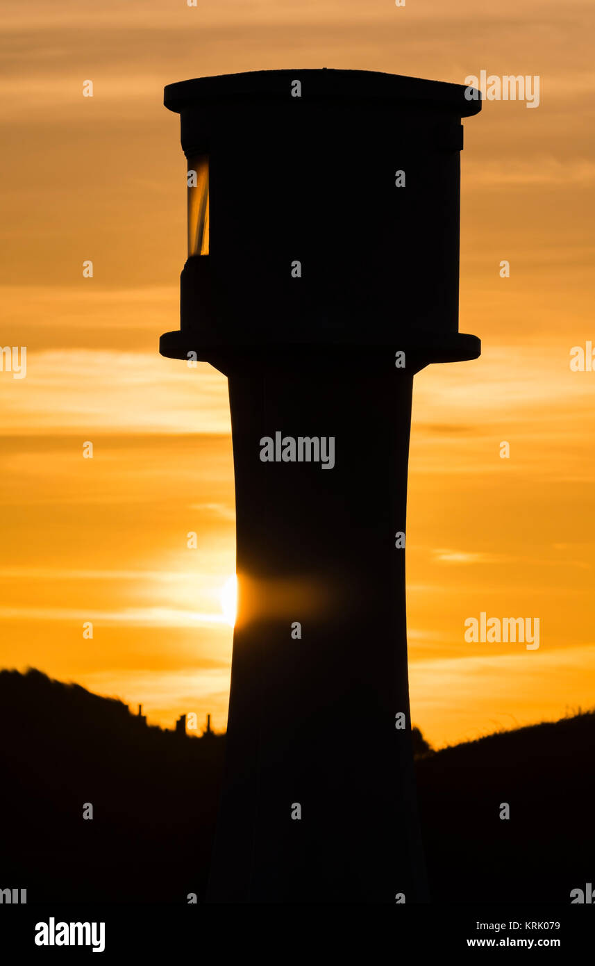 Silhouette einer Leuchtturm gegen orange sky, wie die Sonne, im Vereinigten Königreich. Stockfoto