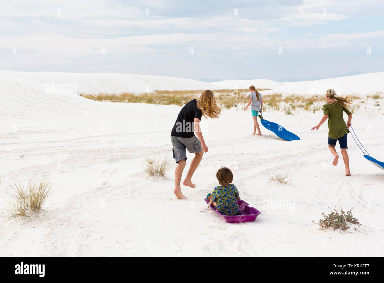 Kaukasischen Jungen und Mädchen spielen auf Schlitten im Sand Stockfoto