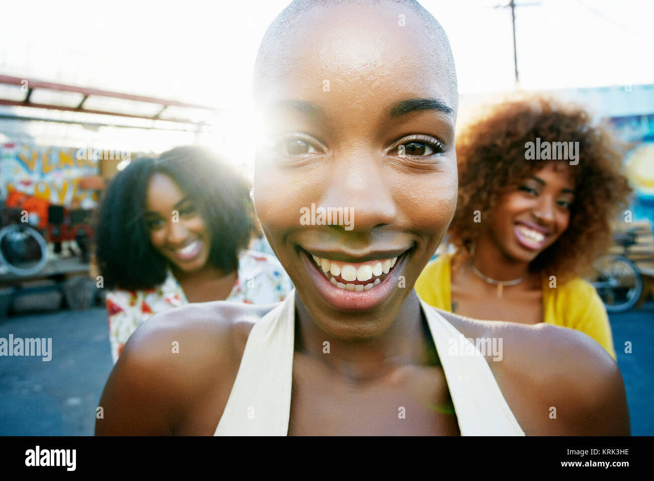 Freunde lächelnd hinter kahlen Frau im Freien Stockfoto