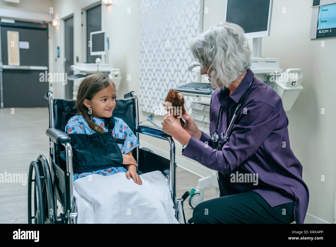 Arzt mit Teddybären zu Mädchen im Rollstuhl Stockfoto