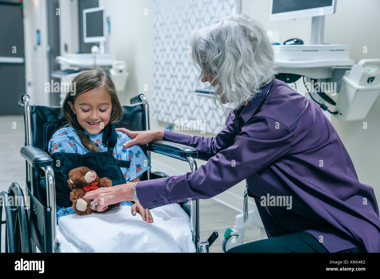Arzt, Teddybären zu Mädchen im Rollstuhl Stockfoto