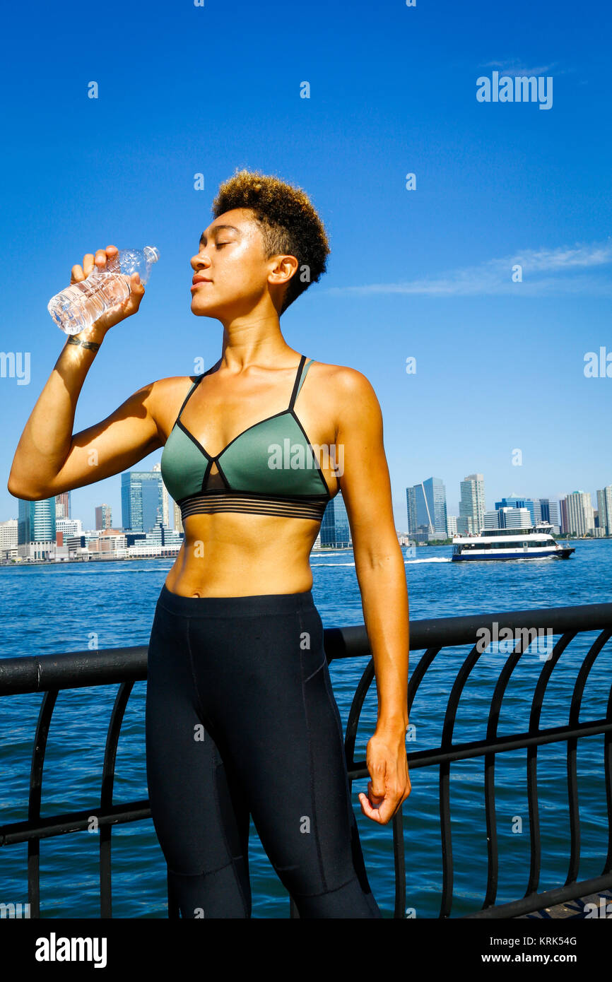 Gemischte Rasse Frau trinkt Wasser im Waterfront Stockfoto