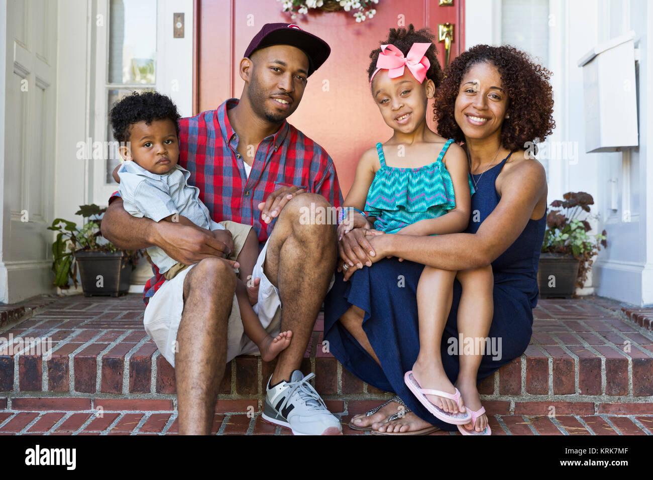 Portrait von lächelnden gemischten Rennen Familie sitzt auf der vorderen Stoop Stockfoto