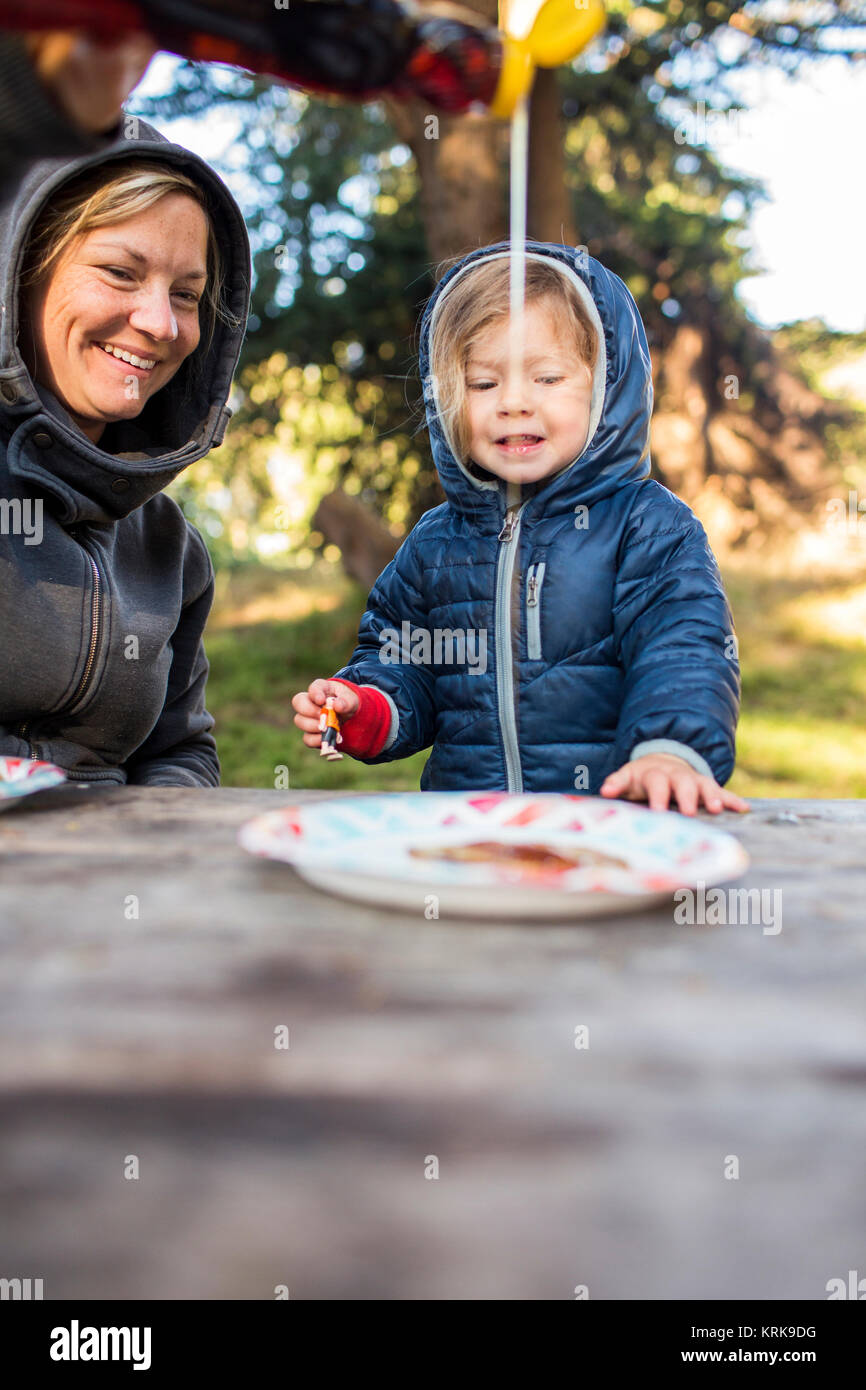 Weißen Mutter gießen Sirup auf Pfannkuchen für Tochter Stockfoto