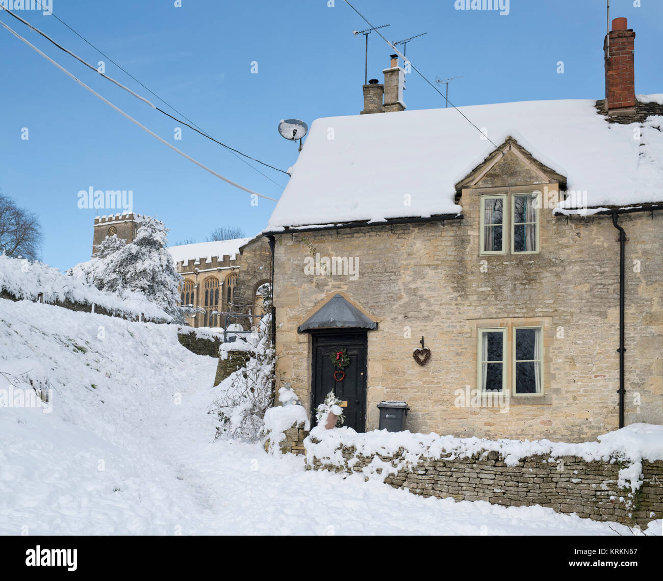 Chedworth Village Cottage und Kirche im Dezember Schnee. Chedworth, Cotswolds, Gloucestershire, England Stockfoto