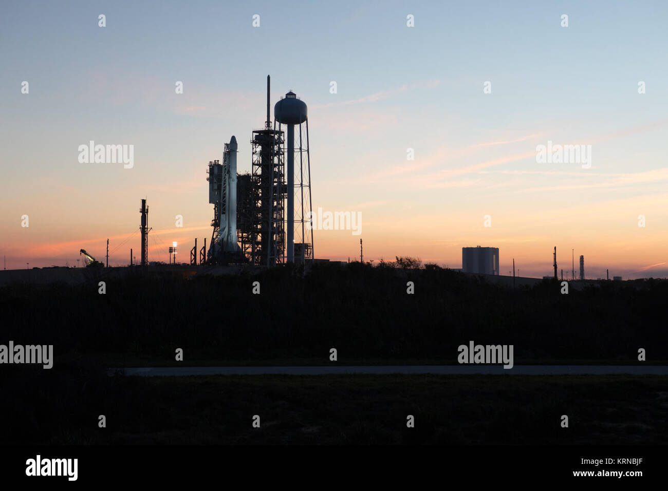 Wie Sonne, eine Falcon 9 Rakete steht bereit für Liftoff auf Launch Complex 39 das Kennedy Space Center A. Der historische Ort ist jetzt von SpaceX unter einer Immobilie unterzeichnet Abkommen mit der NASA betrieben. Im Hintergrund ist das Vehicle Assembly Building. Die Rakete wird ein Drache resupply Raumfahrzeug zur Internationalen Raumstation zu steigern. Liftoff ist für 10:01 Uhr EST am 13.02.18. Auf seiner 10. Commercial resupply Services Mission zur Raumstation, Dragon wird 5.000 Pfund von Zubehör, wie z. B. die Stratosphärische Aerosole und Gas Experiment (SAGE) III Instrument zur weiteren Stu Stockfoto