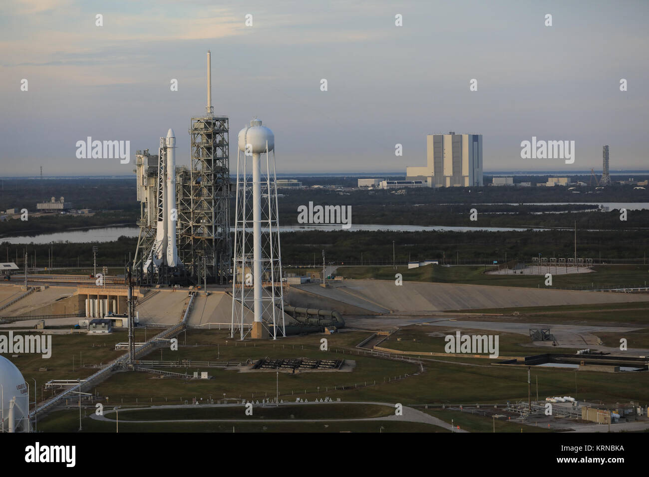 Eine Falcon 9 Rakete steht bereit für Liftoff auf Launch Complex 39 das Kennedy Space Center A. In diesem Luftbild, steht auf dem Launch Pad mit der Vehicle Assembly Building (VAB) im Hintergrund. Rechts von der VAB ist die mobile Launcher, die für das Stapeln der NASA Space Launch System Rakete, der Agentur Orion Raumschiff auf Missionen über den erdnahen Orbit senden verwendet wird. Die Falcon 9 wird ein Drache resupply Raumfahrzeug zur Internationalen Raumstation zu steigern. Liftoff ist für 9:39 Uhr EST. Dragon wird 5.500 Pfund liefert, auf seinen 10 commercial Resupply Stockfoto