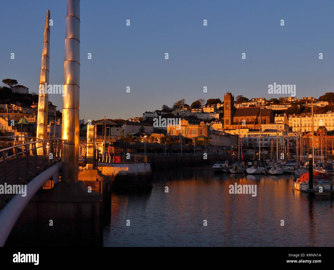 Abendsonne golden über Torquay Harbour mit Hafen Steg im Vordergrund, auf der Suche nach St John's Kirche. Torquay, Devon, Großbritannien. Dezember 2017. Stockfoto