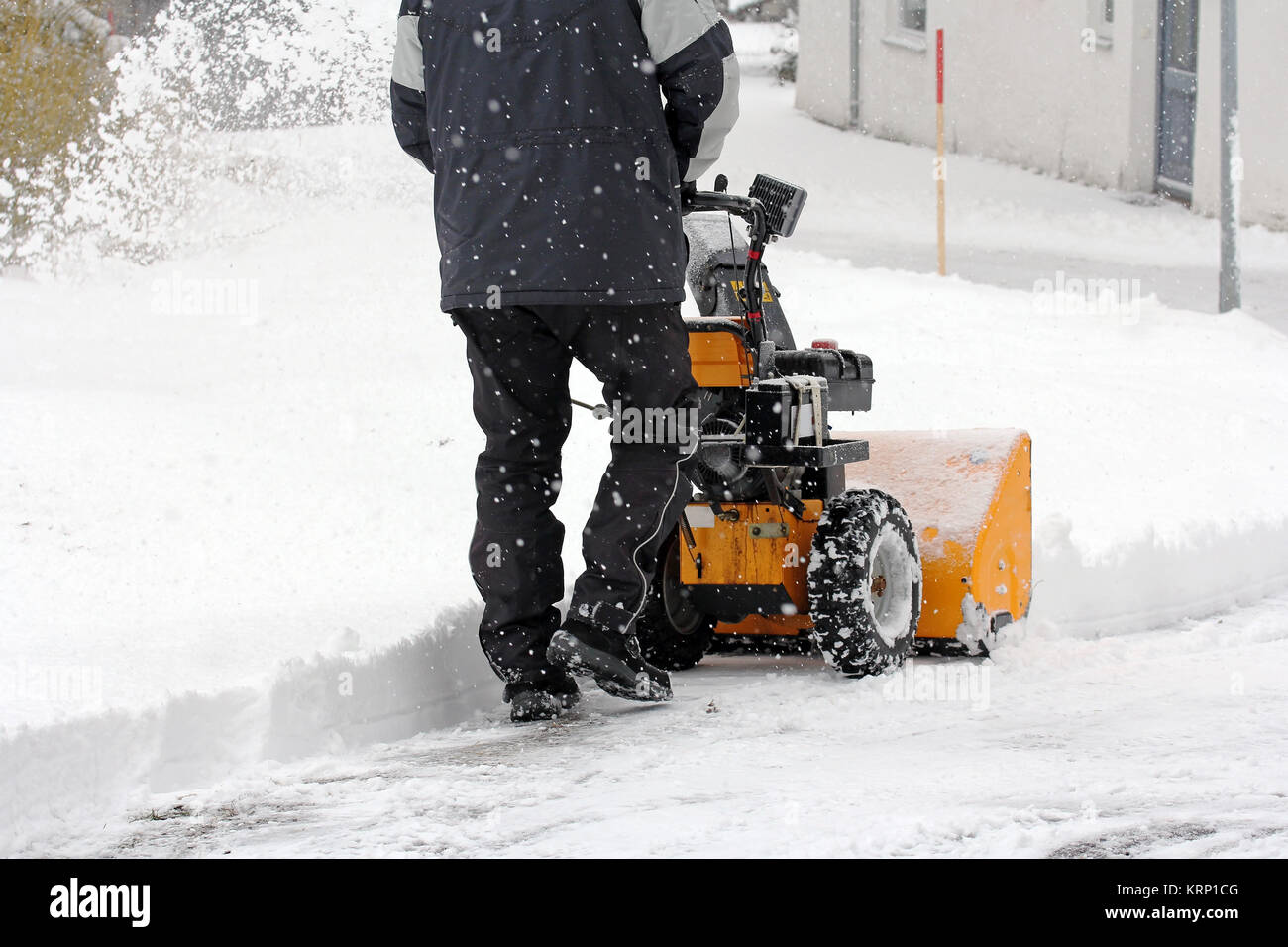 Ein Mann gesteht Schnee mit einer Schneefräse Stockfoto