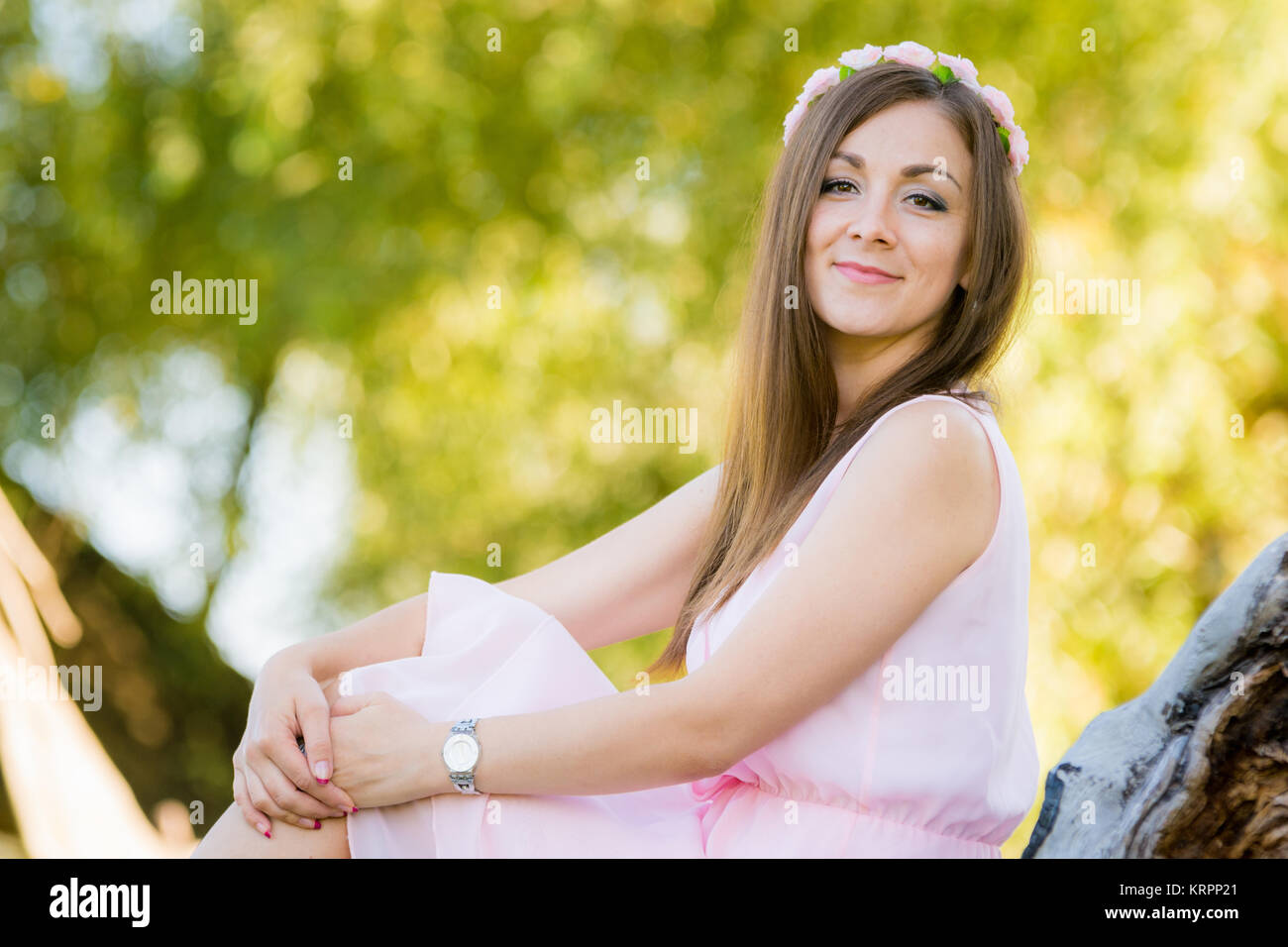 Schönes Mädchen sitzt auf einem Hintergrund beleuchtet von der Sonne-Blätter Stockfoto