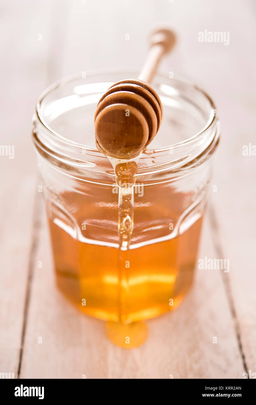 Golden klar Honig im Glas mit Löffel und Nieselregen Stockfoto