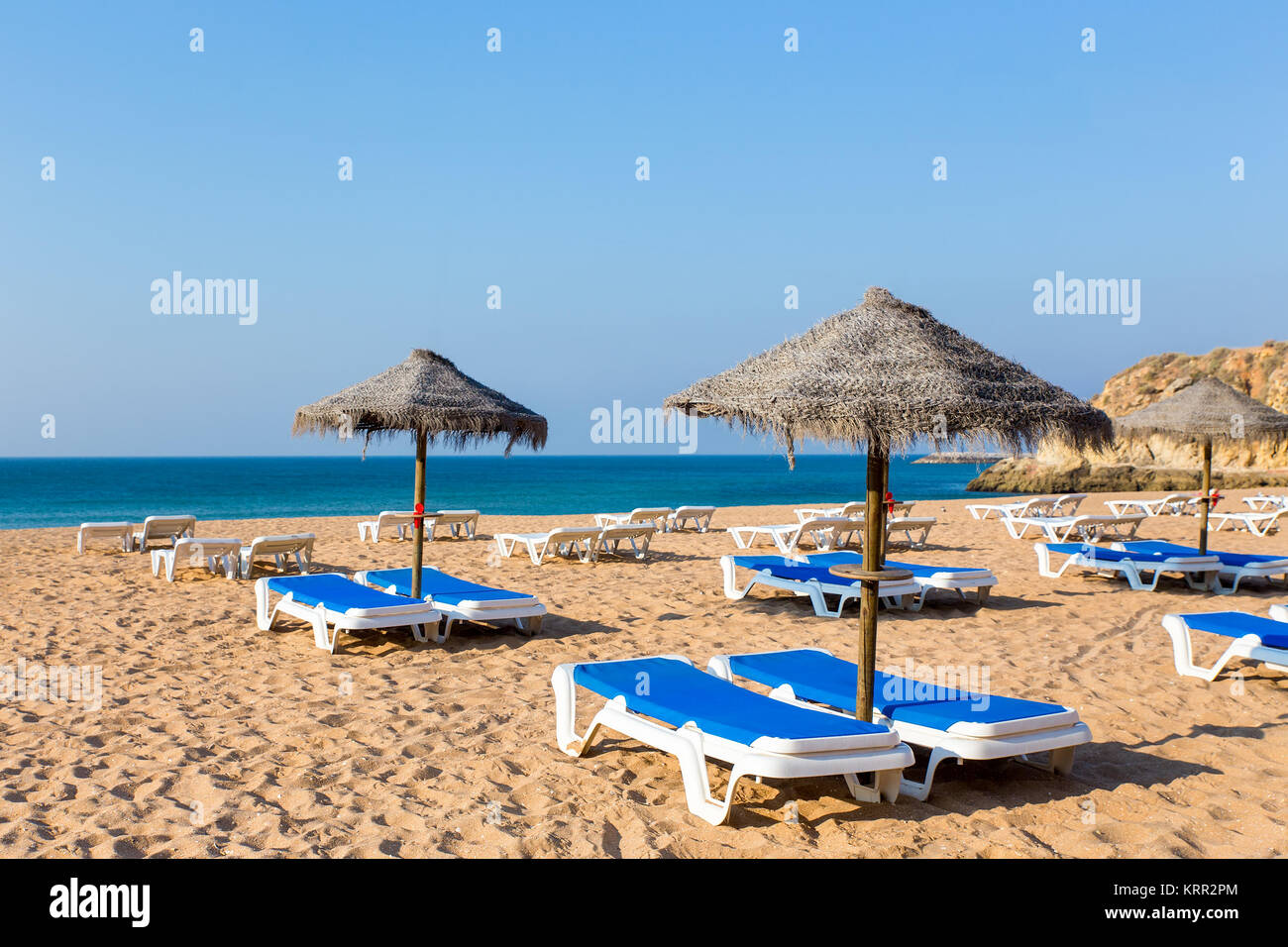 Gruppe wicker Strand Sonnenschirme und Blue Beach Betten Stockfoto