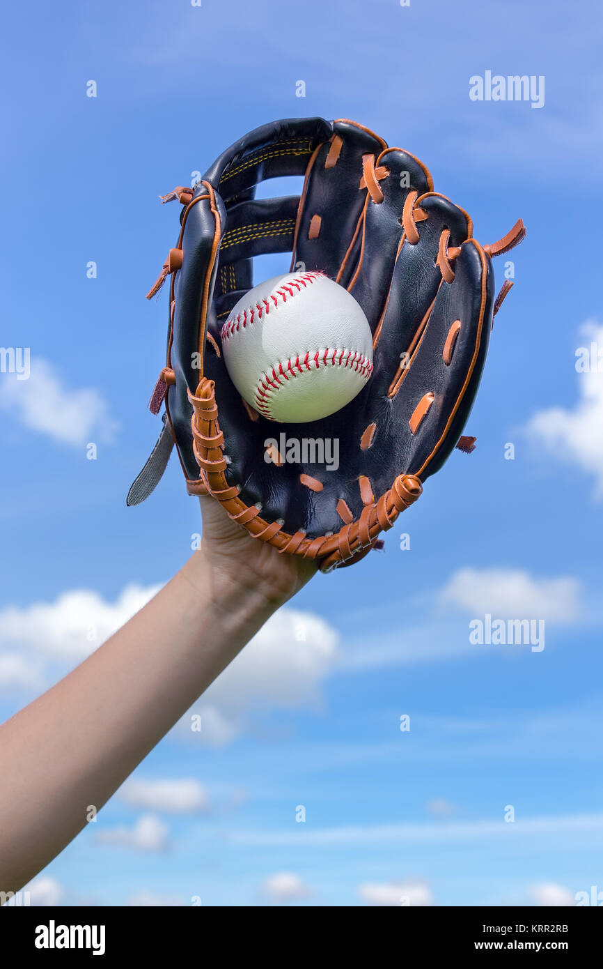 Weibliche arm Holding Baseball mit Handschuh in blauer Himmel Stockfoto