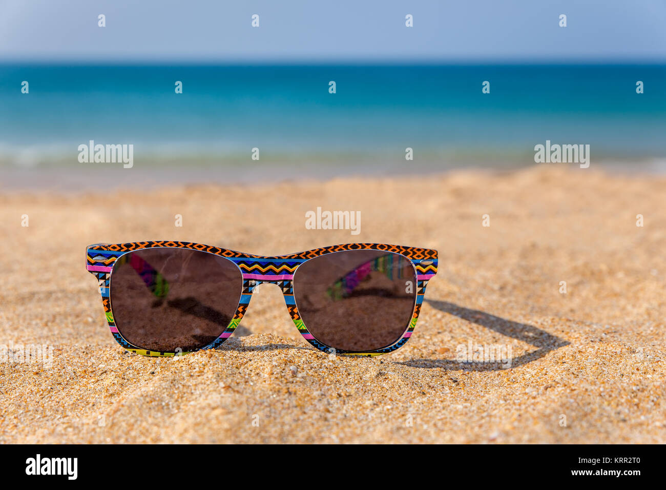 Bunte Sonnenbrille liegen am Strand mit blauem Meer Stockfoto