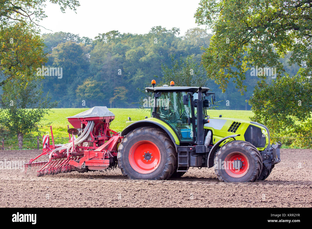 Traktor mit landwirtschaftlichen Maschinen auf landwirtschaftlich genutzten Flächen. Stockfoto