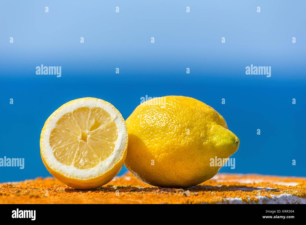 Ganze und halbe gelbe Zitrone mit blauem Himmel und Meer Stockfoto