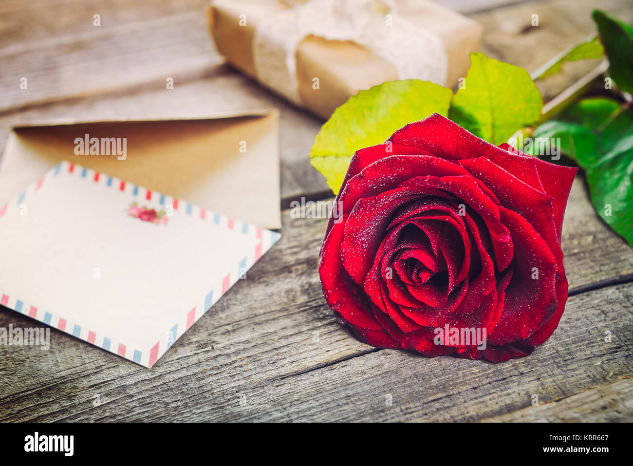 Vintage Happy Valentines Tag Karte. Festliche Komposition mit frischen Rose Blume, Postkarten, Umschläge und Geschenk Box auf dem rustikalen Holztisch. Geschenk für l Stockfoto
