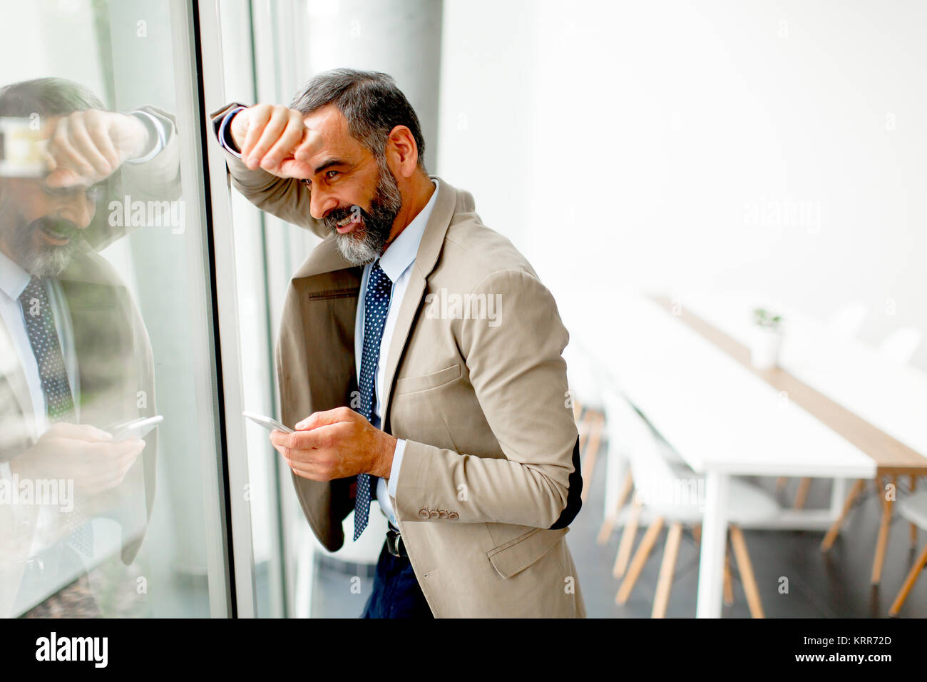 Schöne reife Geschäftsmann mit Mobiltelefon im Büro Stockfoto