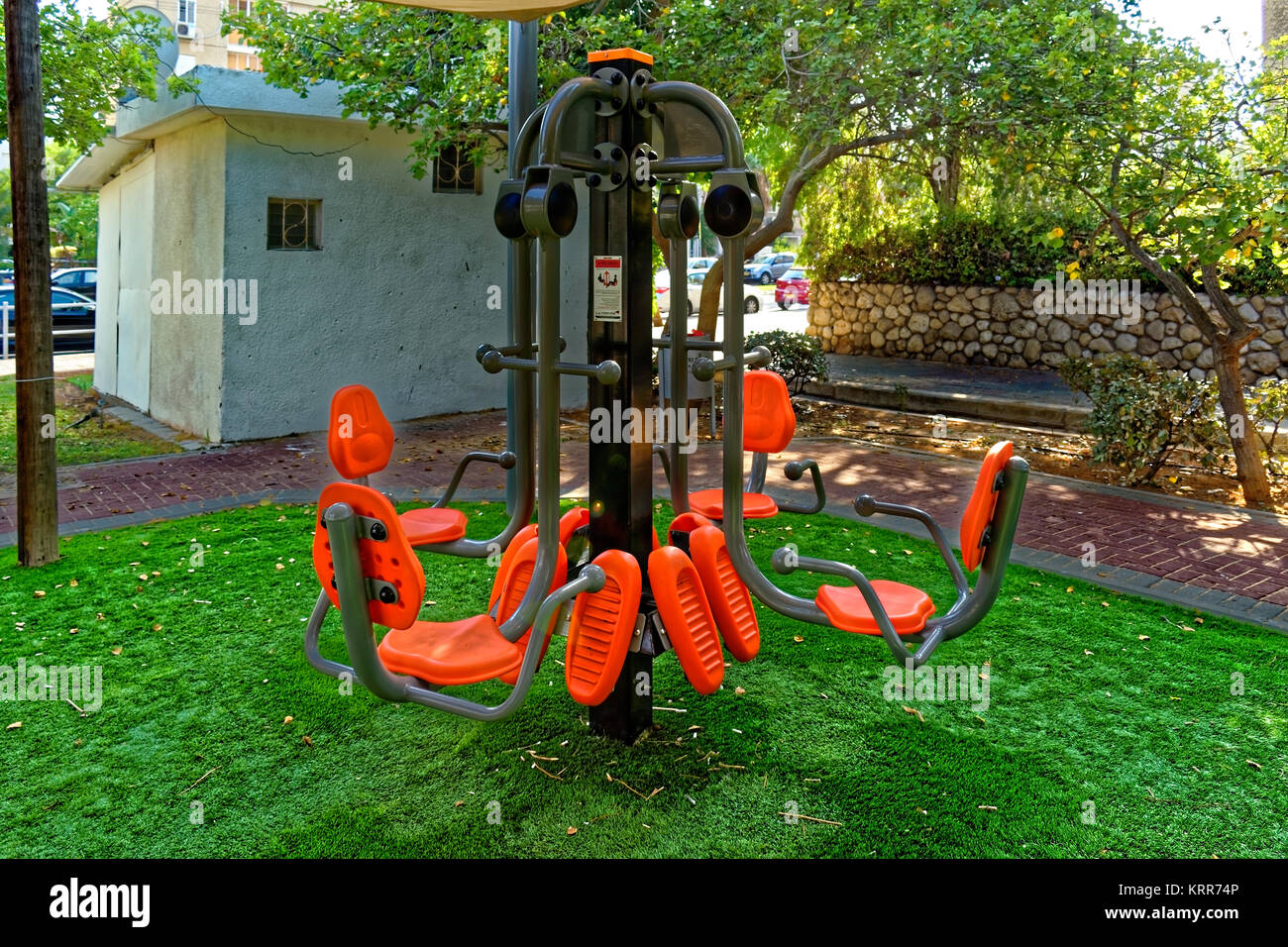 Die öffentliche Ausübung orange Stuhl mit Schwarz und Grau und Orange workout Füße pads. Im Schatten in der Mitte des sonnigen Tag. Mit einem Str Stockfoto