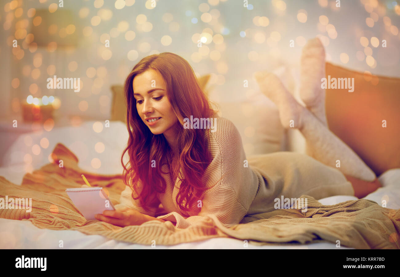 glückliche junge Frau mit Notebook im Bett zu Hause Stockfoto