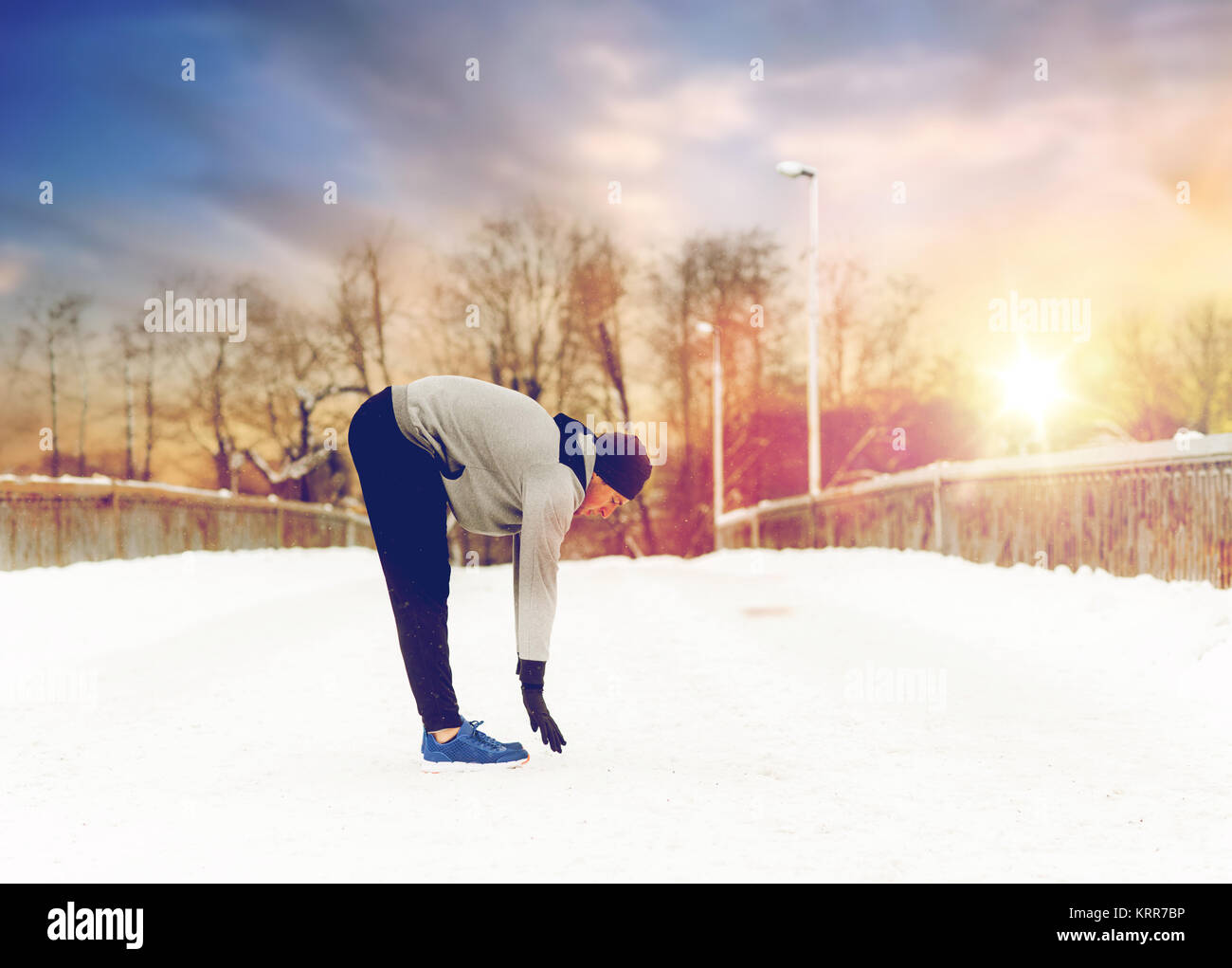Mann, Bewegung und Dehnung Bein auf Winter-Brücke Stockfoto
