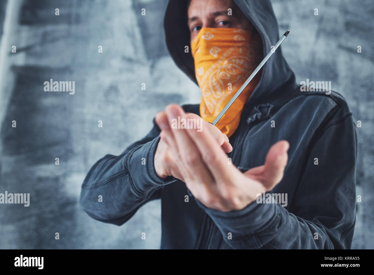 Hooded Bandenmitglieder Kriminelle mit Schal über Gesicht mit Schraubendreher als Waffe Stockfoto