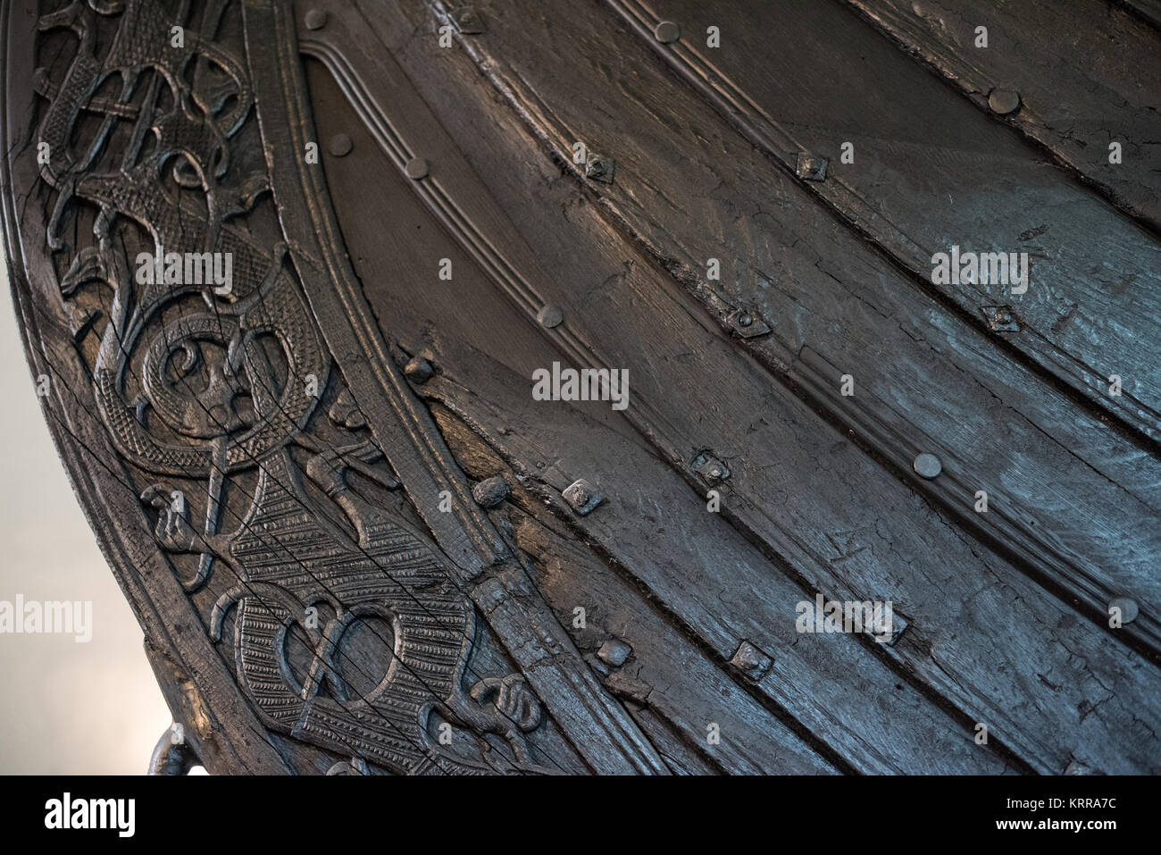 Geschnitztes Detail auf dem Oseberg-Schiff in Oslo | OSLO, Norwegen — Eine enge Spirale aus Schnitzereien von greifenden Bestien windet sich über den Bug des Oseberg-Schiffs in dieser Nahaufnahme im Wikingerschiffmuseum, Tiere, deren Pfoten die Ränder des Schiffes und die Körper der anderen greifen. Dieser ornamentale Stil, der für das Begräbnis von 834 n. Chr. einzigartig ist, definiert das, was Gelehrte den „Oseberg-Stil“ nennen, eines der schönsten überlebenden Beispiele der frühen Wikinger-Holzschnitzerei. Stockfoto
