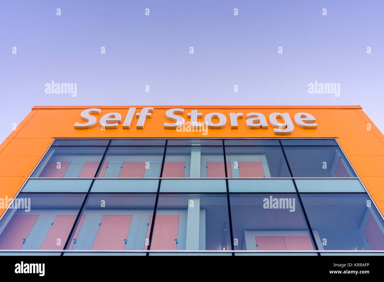 Orangefarbene Gebäude Fassade eines LoknStore Self Storage Einheit gegen den blauen Himmel in England, Großbritannien Stockfoto