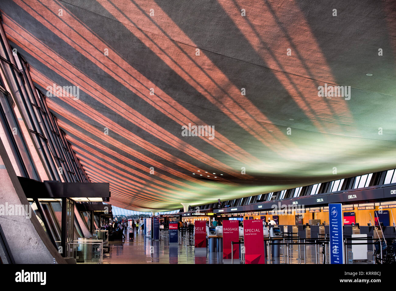 DULLES International Airport Terminal Interior Chantilly Virginia // DULLES, Virginia — das Sonnenlicht am späten Nachmittag strömt durch große Glasfenster auf die Decke des ursprünglichen flügelförmigen Terminalgebäudes am Dulles International Airport in Chantilly, Virginia. Das vom renommierten Architekten Eero Saarinen entworfene und 1962 eröffnete Hauptterminal ist bekannt für sein unverwechselbares, geschwungenes Dachdesign. Dulles ist einer von drei großen Flughäfen in der Metropolregion Washington DC, die sowohl nationale als auch internationale Flüge abwickelt. Das modernistische Gebäude gilt als architektonisches Landhaus Stockfoto
