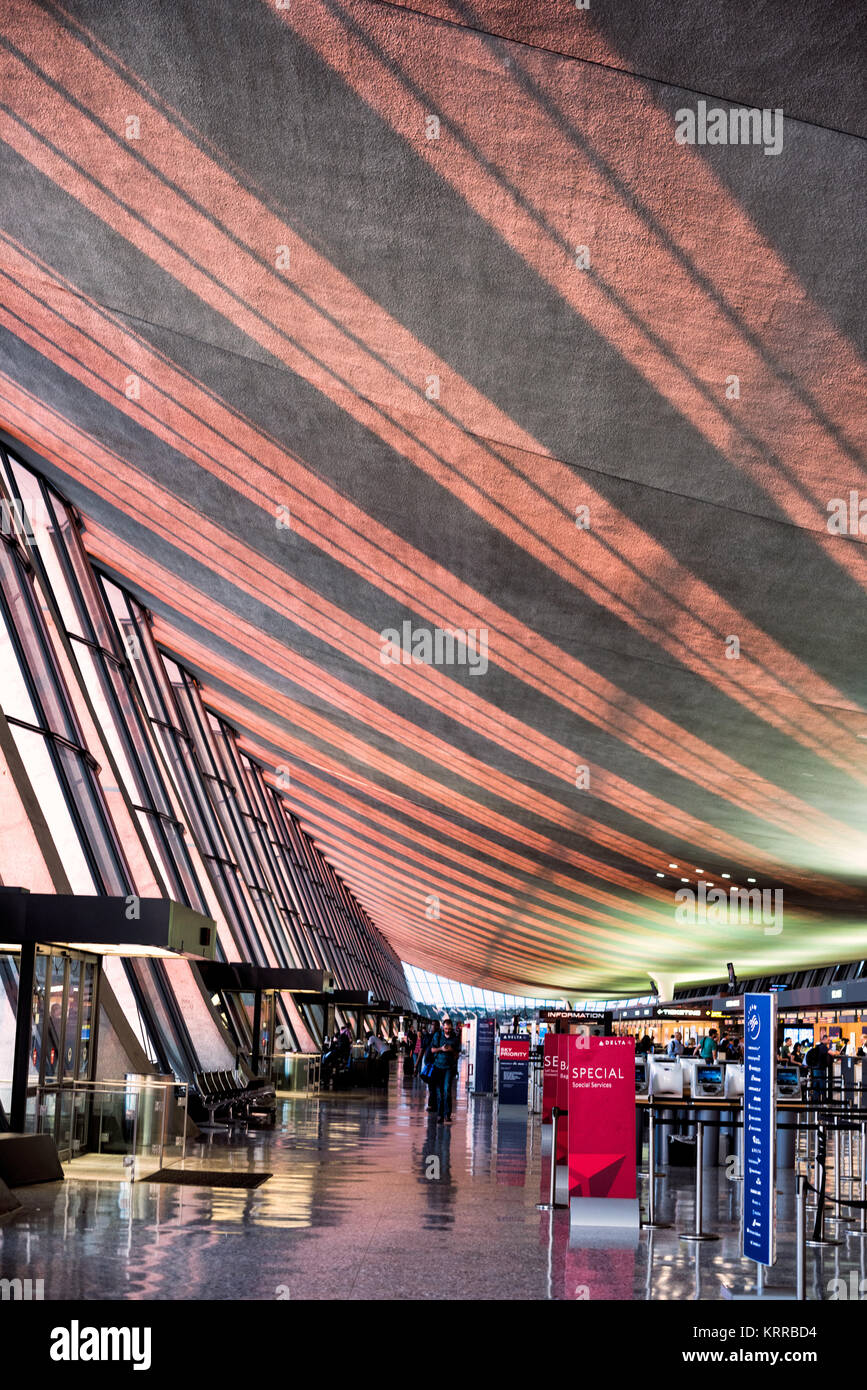 DULLES International Airport Terminal Interior Chantilly Virginia // DULLES, Virginia — das Sonnenlicht am späten Nachmittag strömt durch große Glasfenster auf die Decke des ursprünglichen flügelförmigen Terminalgebäudes am Dulles International Airport in Chantilly, Virginia. Das vom renommierten Architekten Eero Saarinen entworfene und 1962 eröffnete Hauptterminal ist bekannt für sein unverwechselbares, geschwungenes Dachdesign. Dulles ist einer von drei großen Flughäfen in der Metropolregion Washington DC, die sowohl nationale als auch internationale Flüge abwickelt. Das modernistische Gebäude gilt als architektonisches Landhaus Stockfoto