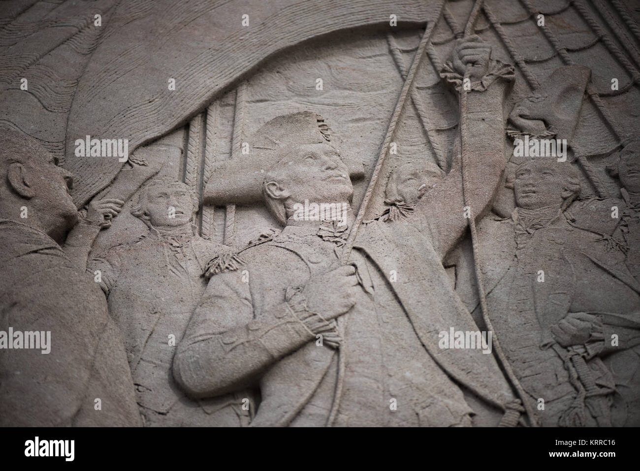 John Paul Jones Memorial Relief Panel Washington DC // WASHINGTON DC — die Relief-Platte auf dem Pylon des John Paul Jones Memorial steht im West Potomac Park neben der National Mall zeigt den dramatischen Moment des Hissens der ersten amerikanischen Flagge an Bord eines Marineschiffs. Dieses Tableau erinnert an einen entscheidenden Moment in der Geschichte der Marine und unterstreicht seine Beiträge zur Gründung der amerikanischen Marine power​​. Die Bronzestatue des Kriegshelden aus dem Unabhängigkeitskrieg, die von Charles Henry Niehaus geschaffen wurde, erhebt sich auf einem Marmorsockel, umgeben von Springbrunnen und Basreliefs, die Szenen aus Jones' Leben darstellen. Stockfoto
