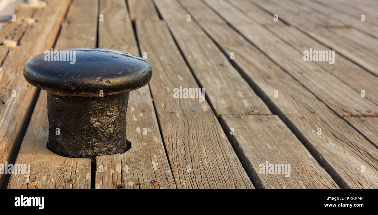 Schwarz rostige Poller Liegeplatz auf der Holzterrasse Hintergrund. Unscharfe, Detailansicht mit Details. Platz kopieren Stockfoto