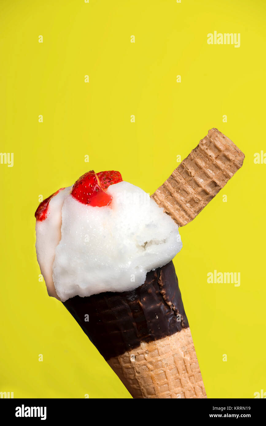 Zitrone Eis mit Erdbeeren Stücke in einer Waffel auf gelbem Hintergrund Stockfoto