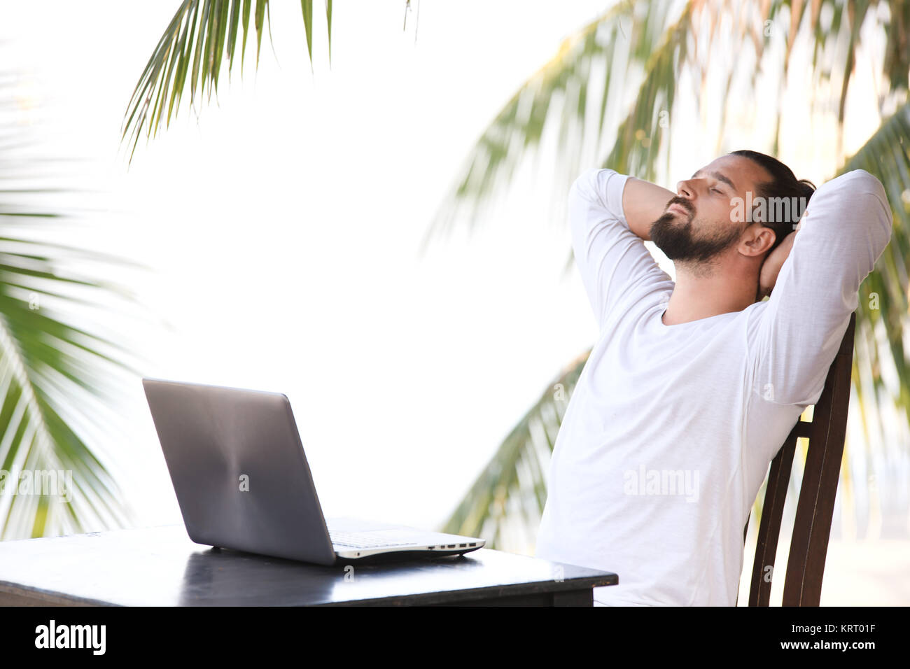 Man entspannt am Strand mit Laptop, Freelancer Arbeitsplatz, Traumjob Stockfoto