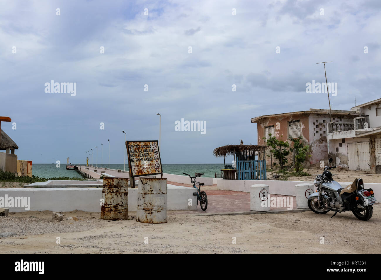 Ein Fahrrad- und ein Motorrad in der Nähe von einem Pier und alte Wetter geschlagen Häuser in der Nähe von Progesso Yucatan Mexiko 7 - 06 - 2017 geparkt Stockfoto