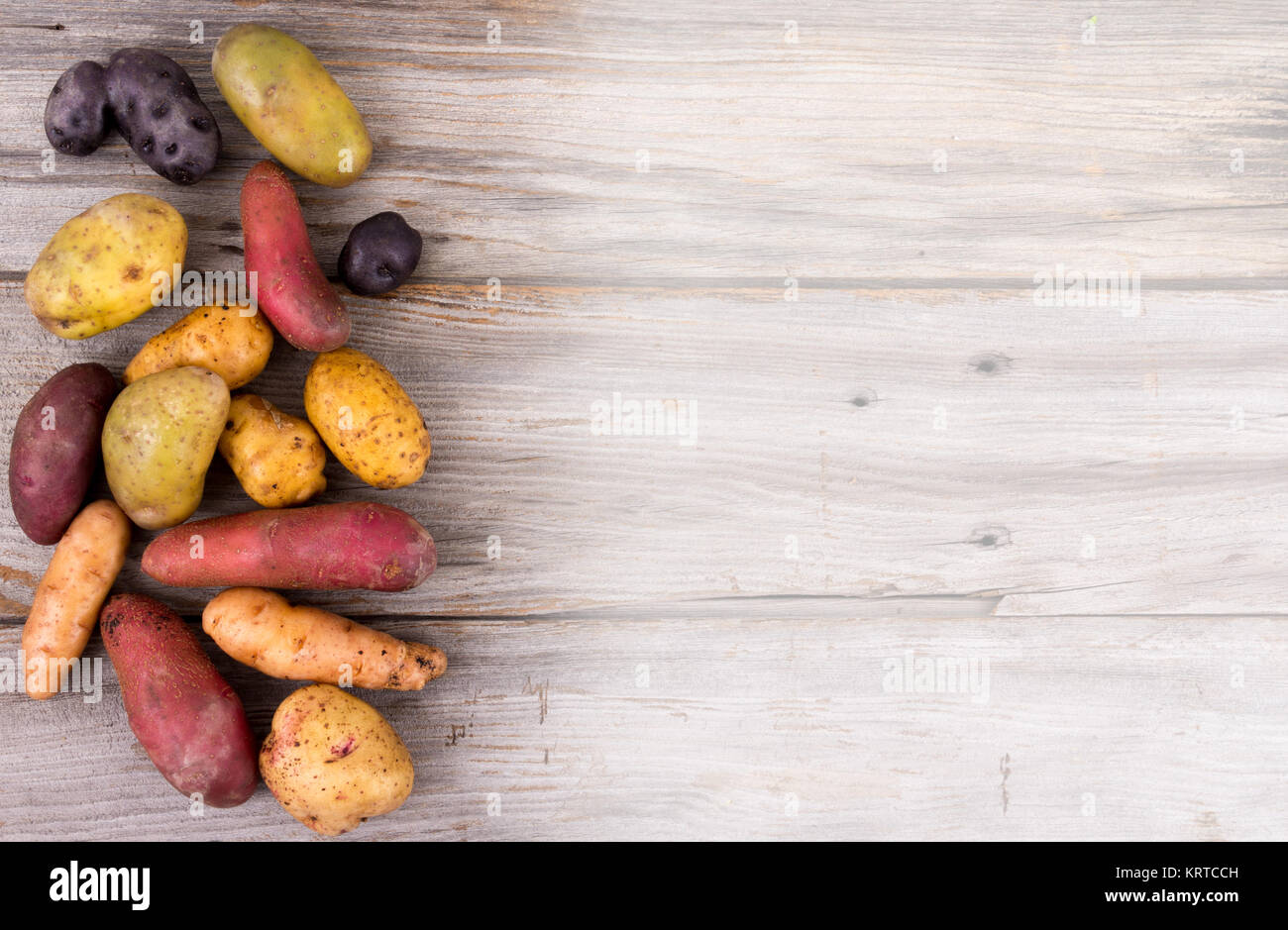 Frische organische Kartoffeln Sorten über Planke rustikalen Hintergrund Stockfoto