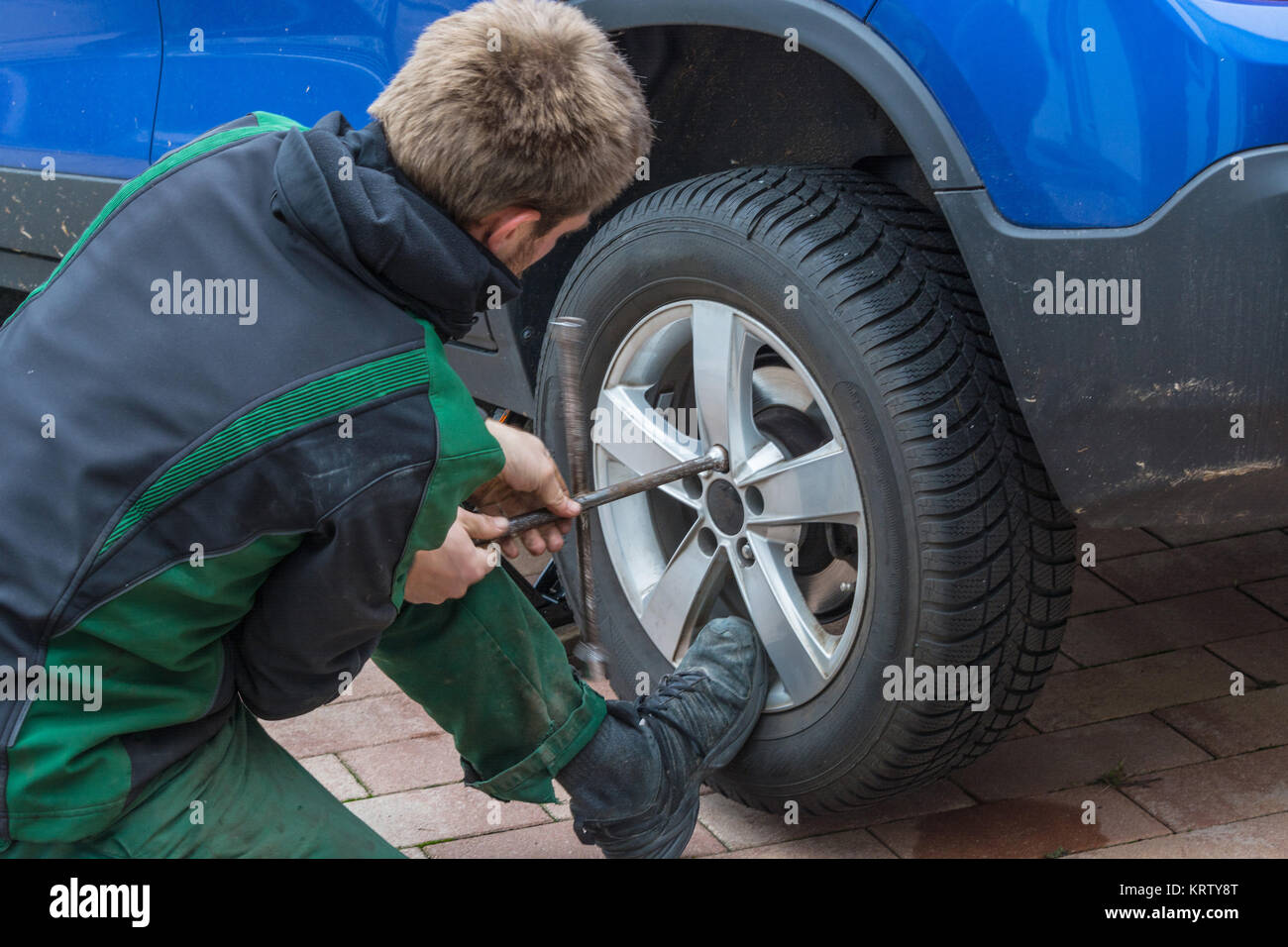 Junger Mann beim Tauschen der Autoreifen. Von Sommerreifen auf Winterreifen ein seinem Auto. Stockfoto