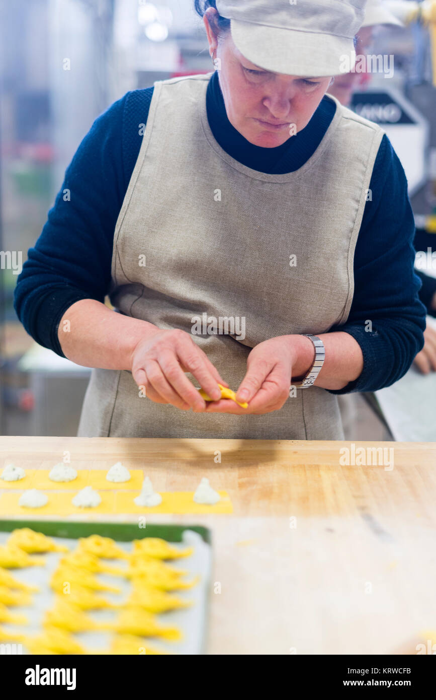Professionelle ältere 70er Jahre 80er Jahre Dame, die handgemachte Ricotta Tortelli con la coda gefüllte Pasta in einer professionellen Küche mit frischen Zutaten zubereitet. Stockfoto